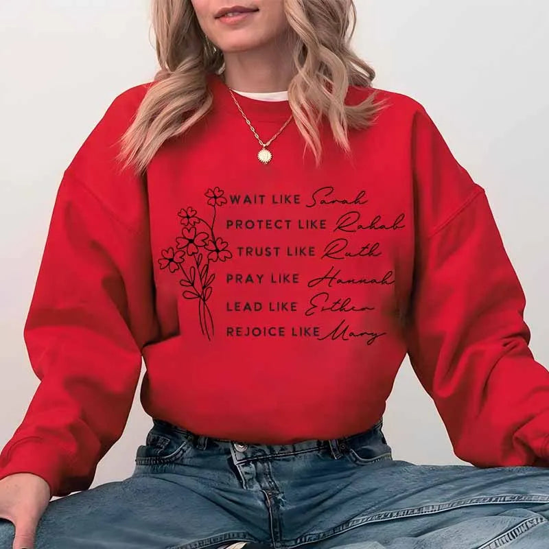 A red sweatshirt featuring black text listing biblical figures like Sarah, Rachel, Ruth, Hannah, Esther, and Mary.