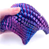A hand holds a purple 3D printed articulated starfish fidget toy with textured, scale-like surfaces.