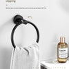 A black towel ring is safely hung on a white wall, demonstrating its ability to be turned up and down.