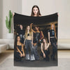 A photo of six young women posing with a black microfiber fleece throw blanket.