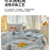 A light blue and white striped quilt featuring playful cartoon prints, displayed on a bed.