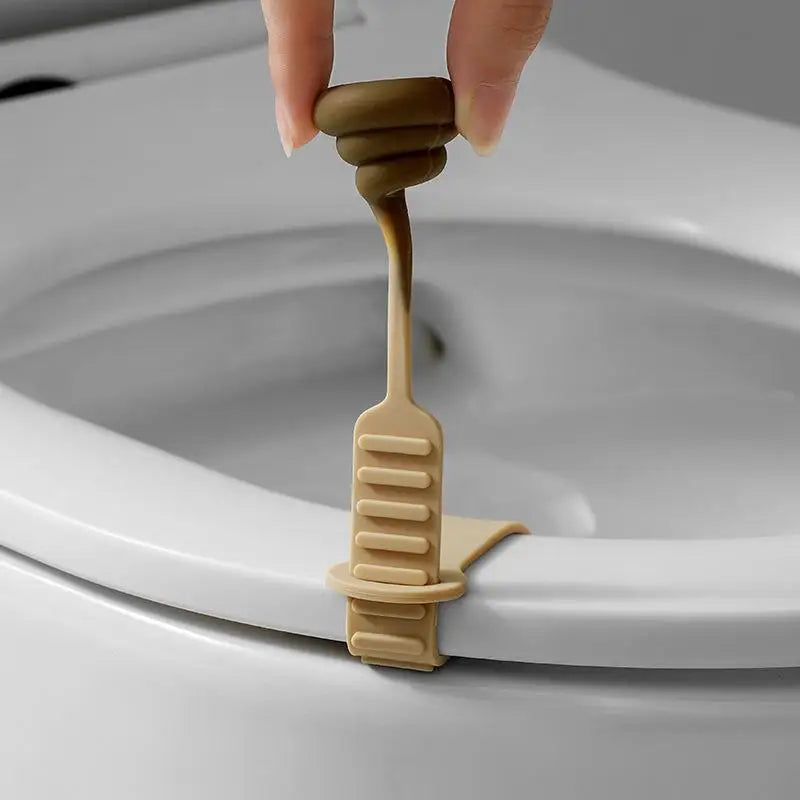 A hand is lifting a beige plastic toilet lid lifter from the rim of a white toilet bowl.