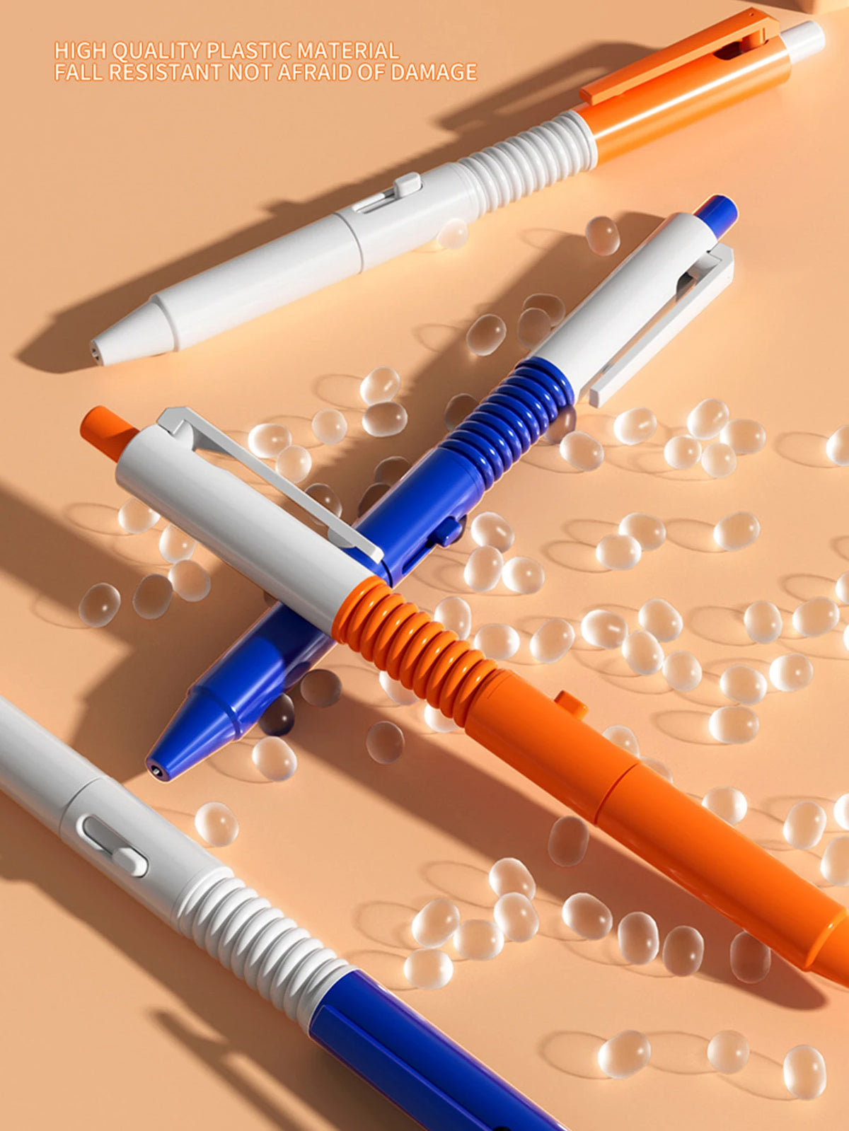 Three plastic pens in orange, white, and blue are shown spraying water on a light background.