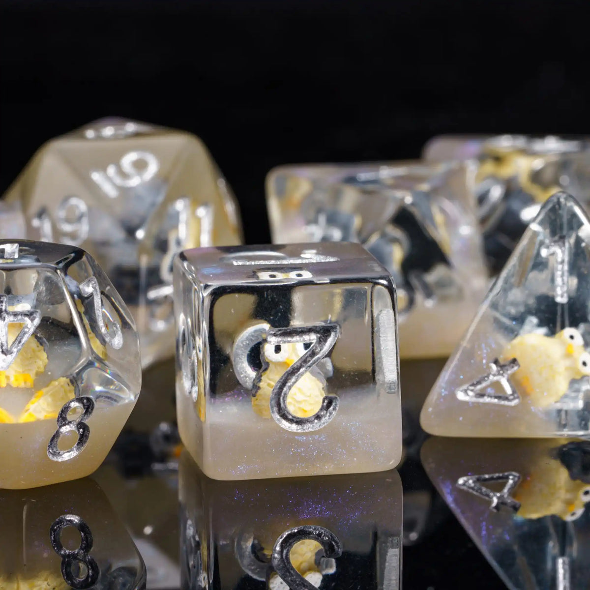 A close-up of a set of clear resin dice featuring adorable animal figures and numbers on a reflective surface.