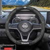 Interior view of a Nissan steering wheel with carbon fiber patterned grips and controls.