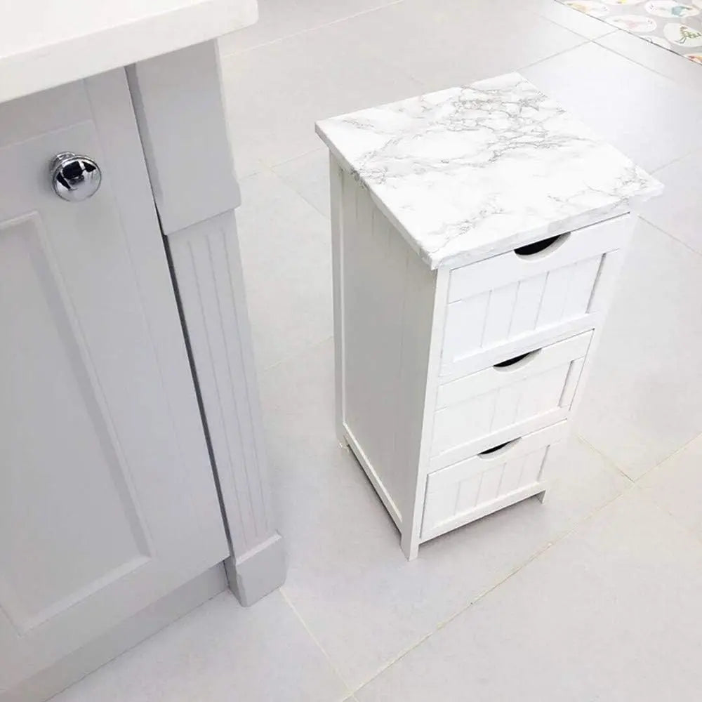 White cabinet with marble top and drawers on a light tile floor.