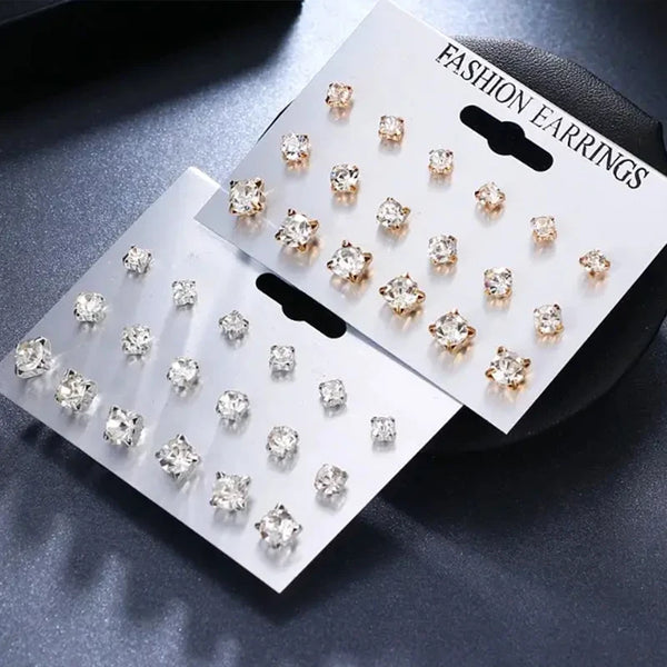 A set of classic rhinestone stud earrings displayed on a card against a dark background.