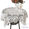 White lace tablecloth with an embroidered rose design set on a table.