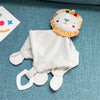 A white elephant plush toy with an orange and striped hood, teether, rattle, and comfort blanket lying on a blue fabric.