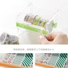 A clear plastic storage box holds rolls of decorative washi tape and a green cutting tool.