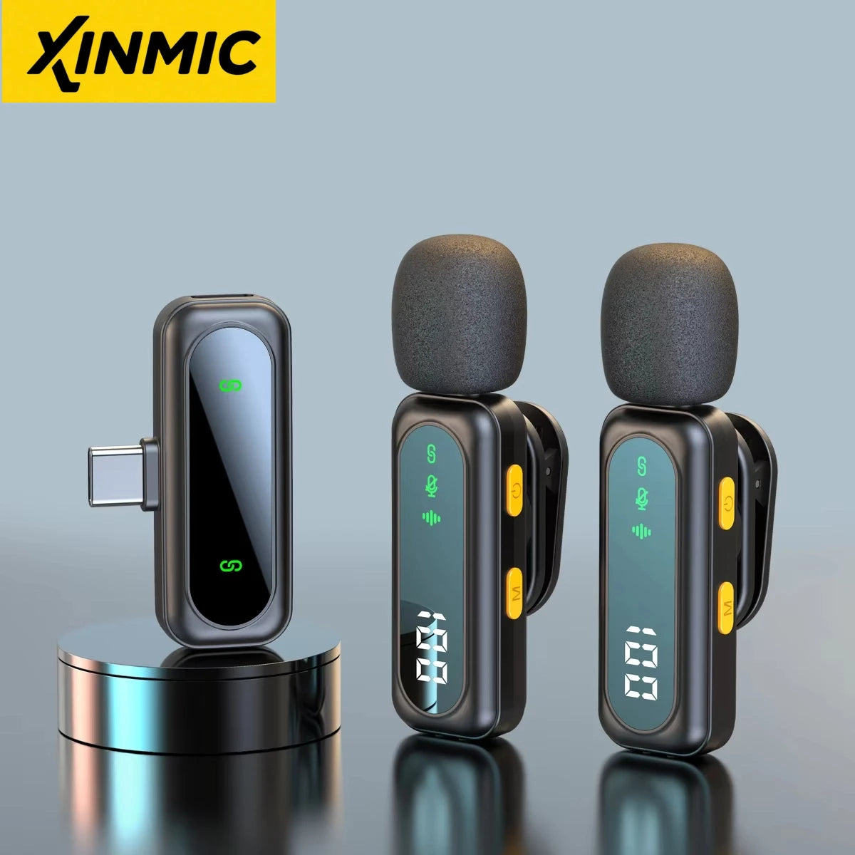 A pair of black wireless lavalier microphone transmitters resting on a reflective surface.