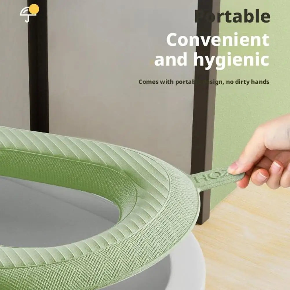 A hand is holding a green soft EVA toilet seat cover, designed for convenient and hygienic use.