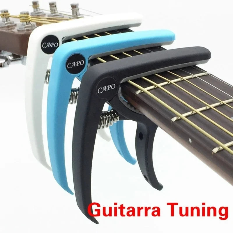 A set of adjustable white and blue guitar capos with built-in bridge pin pullers shown next to a guitar neck.