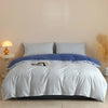 A light blue quilted duvet cover set with matching pillowcases on a bed against a plain wall.
