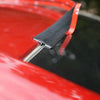 A close-up of a black rubber seal strip being applied to the edge of a red car body.