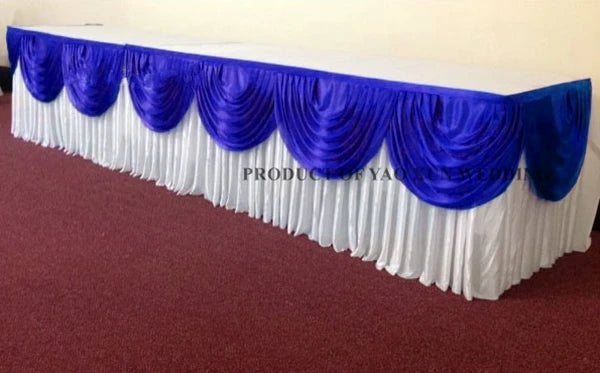Elegant ice silk table skirt in royal blue and white with matching top swag displayed on a table.