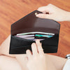 A hand is opening a black slim RFID-blocking PU leather wallet with card slots.