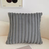A gray, ribbed plush decorative pillow cover resting on a light-colored sofa.