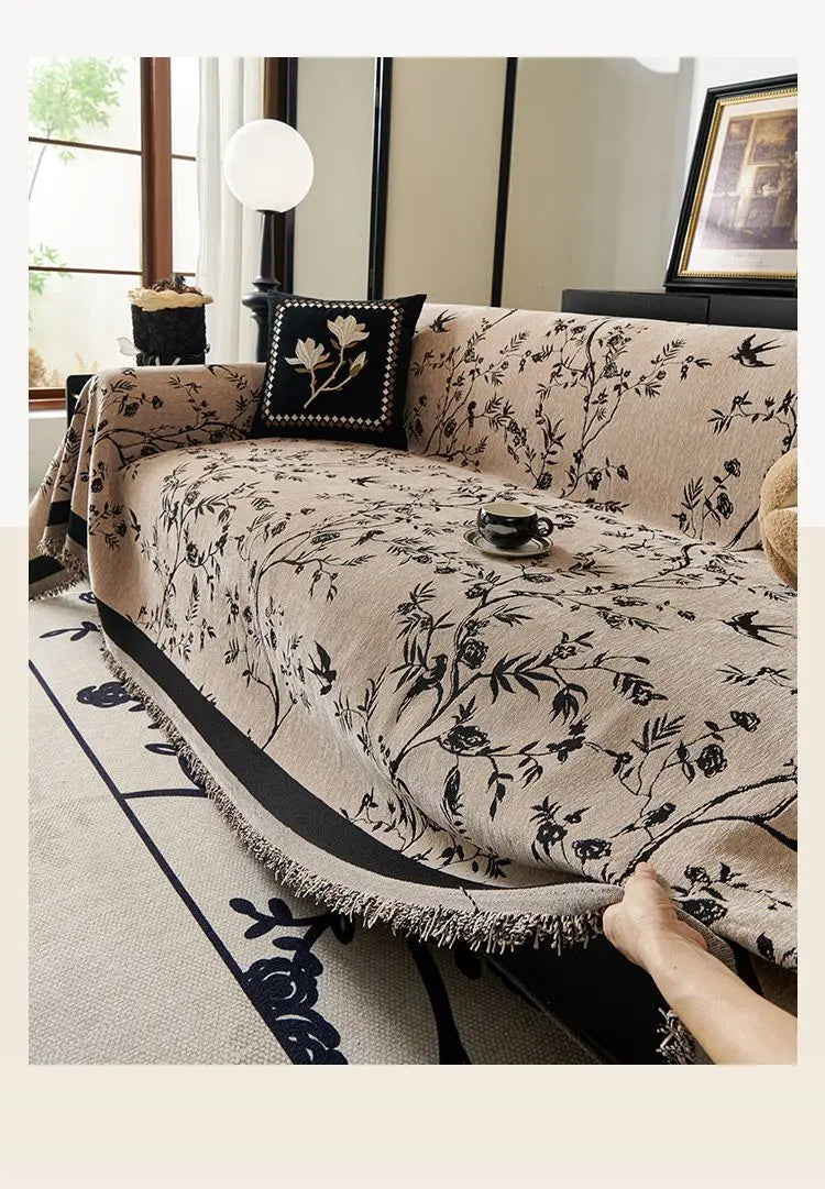 Beige bestickter Chenille-Sofasbezug, drapiert über ein helles Sofa mit dunklen Akzenten.