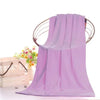 A purple ultra-soft microfiber bath towel hanging on a wooden hanger with a floral background.