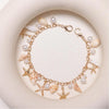Gold chain necklace featuring starfish and pearl charms on a white background.