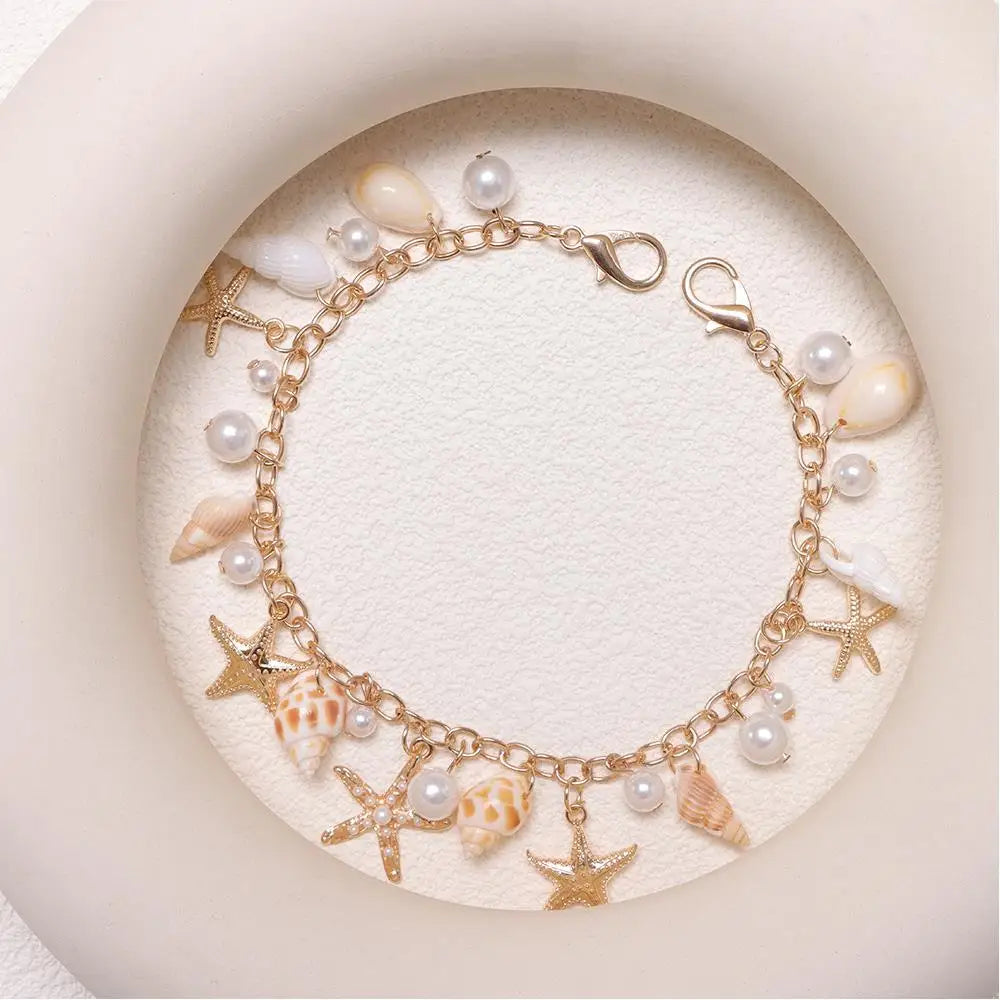 Gold chain necklace featuring starfish and pearl charms on a white background.