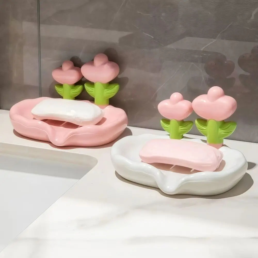 Pink and green tulip shaped soap dishes with white soap bars displayed on a marble surface.
