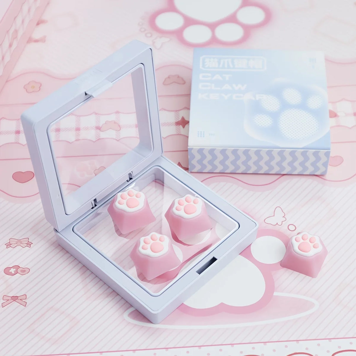 A clear plastic case holds pink silicone cat paw keycaps and a box for MX switches.