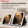 Folding makeup mirror with an intelligent touch screen and multicolor light source displayed on a white surface.