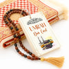 A set of portable Islamic Dua cards with wooden beads and tassels resting on a beige towel.