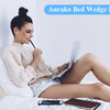Eine Frau entspannt sich im Bett mit einem Aurako Bed Wedge Kissen und einem Laptop.