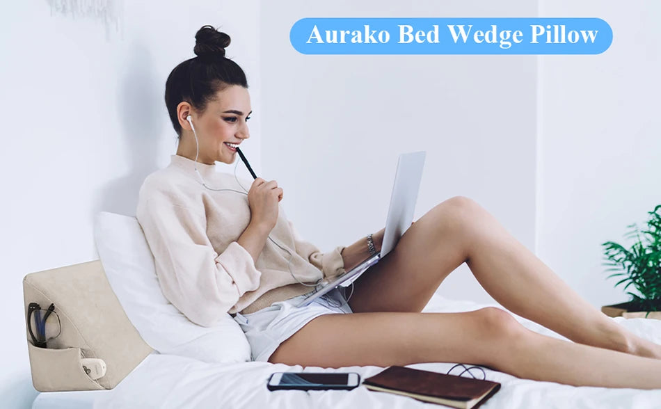 Eine Frau entspannt sich im Bett mit einem Aurako Bed Wedge Kissen und einem Laptop.