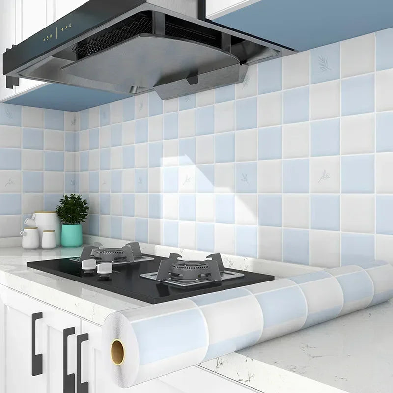 A modern kitchen featuring a white tiled splashback and a black cooktop with a stainless steel hood above.