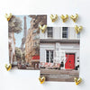A set of twelve gold heart-shaped refrigerator magnets displayed against a background featuring the Eiffel Tower and Parisian