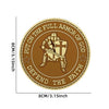 A round brown embroidered patch featuring a knight's shield with a cross and sword, surrounded by text encouraging defense of