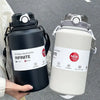 A black 2L insulated stainless steel tumbler with a lid and straw is held by a person.