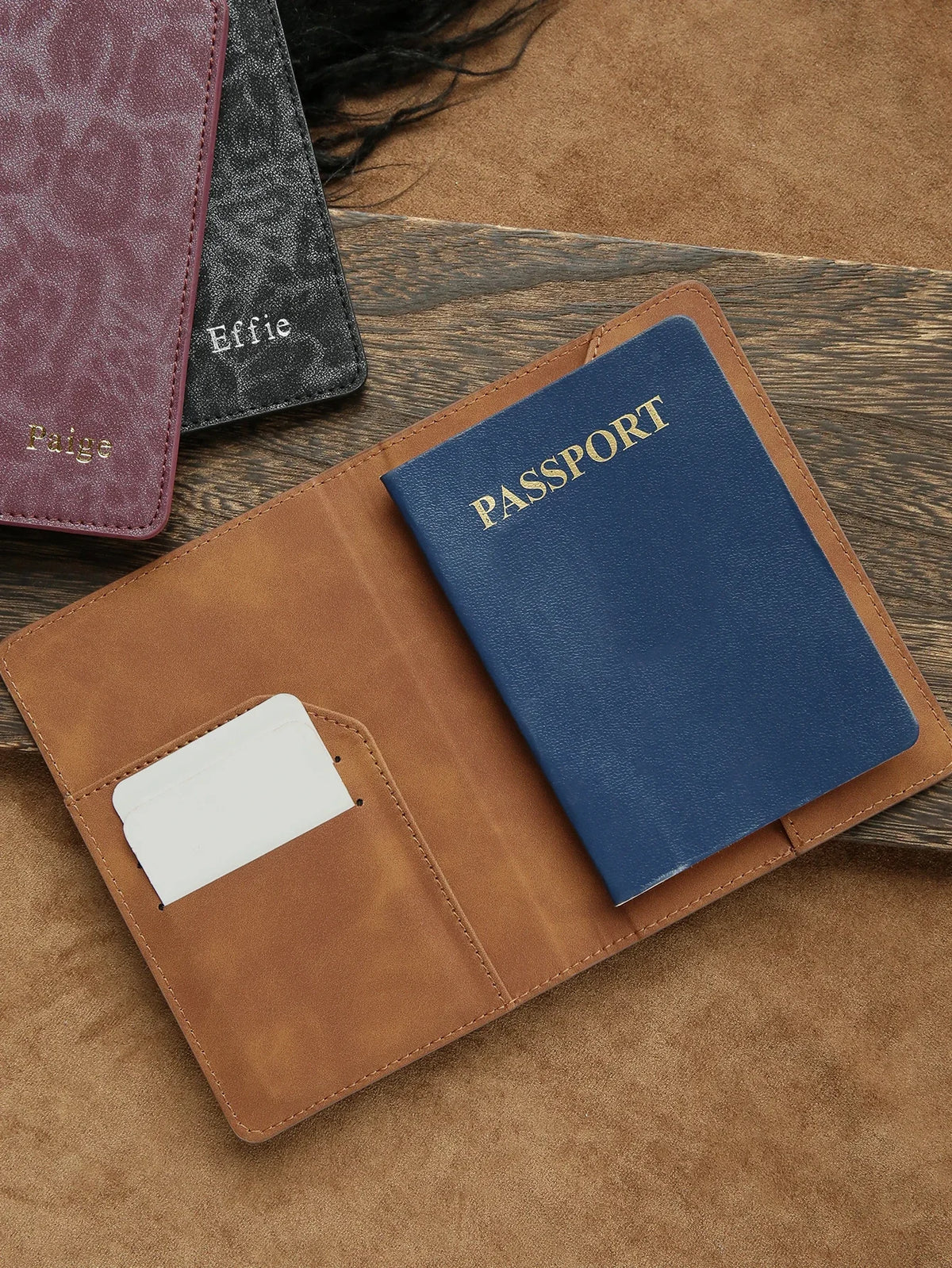 A brown leather passport holder with a navy blue passport and a white card, resting on a tan surface.