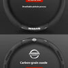 A black carbon fiber steering wheel cover with ventilation holes and a carbon-grain suede finish.