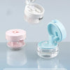 A portable denture case with a lid and cleaning brush storage is shown in pink and light blue colors.