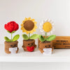 Three handmade crochet flowers in red, yellow, and white on mossy bases for home decor