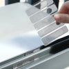 A hand applies a self-adhesive window screen repair patch to a window frame.