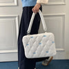 A person is holding a white quilted laptop shoulder bag with blue bows and padded protection.