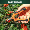 A hand holds an orange and black stainless steel garden scissor with a non-slip handle, positioned among green foliage and re