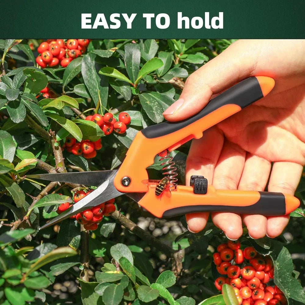 A hand holds an orange and black stainless steel garden scissor with a non-slip handle, positioned among green foliage and re