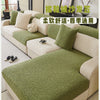 A light beige sofa covered with a green jacquard fleece fabric and matching pillows in a bright room.