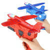 A child's hand is launching an orange foam glider plane toy from a catapult set.