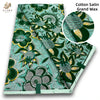 Green and teal cotton satin grand wax fabric featuring floral and leaf patterns with gold accents