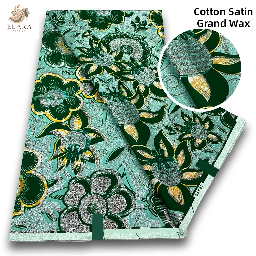 Green and teal cotton satin grand wax fabric featuring floral and leaf patterns with gold accents