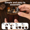 Hands assemble a wooden dollhouse miniature kit featuring dark wood and small glass bottles.