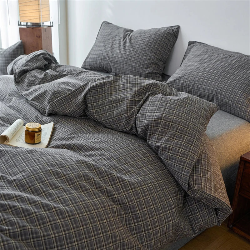 A plaid duvet cover in gray and black tones is displayed on a bed with pillows and natural light.